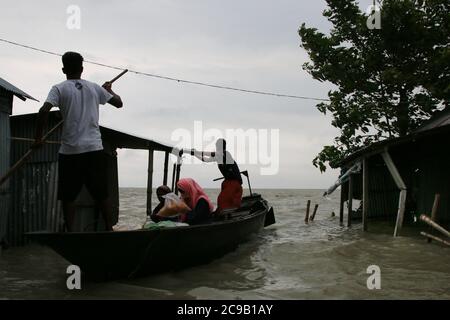 Les personnes touchées par les inondations utilisent des bateaux au lendemain à Dohar.un tiers du Bangladesh est sous l'eau après certaines des pluies les plus abondantes depuis une décennie, laissant plus de 3 millions de personnes affectées par des maisons et des routes dans des villages inondés, ont déclaré des responsables du Centre de prévision et d'alerte des inondations (FFWC). Banque D'Images