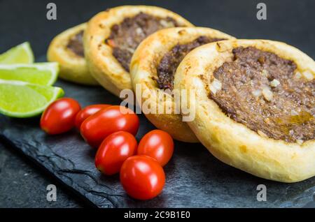 Délicieux plats libanais (arabes), de véritables sfihas sur une assiette en ardoise avec des tomates et des citrons. Banque D'Images