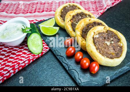 Délicieuse cuisine libanaise (arabe), véritables sfihas sur une plaque d'ardoise avec tomates, citrons et labreh (caillé) à l'arrière-plan avec le traditionnel libanais Banque D'Images