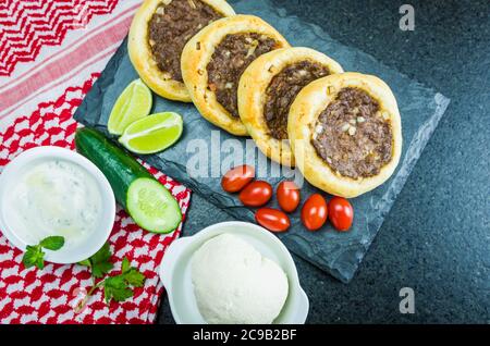 Délicieuse cuisine libanaise (arabe), véritables sfihas sur une plaque d'ardoise avec tomates, citrons et labreh (caillé) à l'arrière-plan avec le traditionnel libanais Banque D'Images