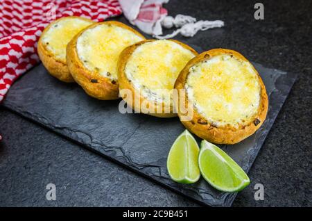 Délicieuse cuisine libanaise (arabe), sfiha au gratin avec du labneh et du fromage sur fond de pierre d'ardoise noire et keffiyeh libanais traditionnel. Banque D'Images