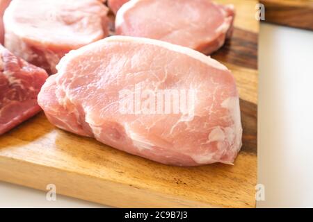 Les côtelettes de filet de porc cru désossées sont rapprochées de la planche à découper en bois Banque D'Images