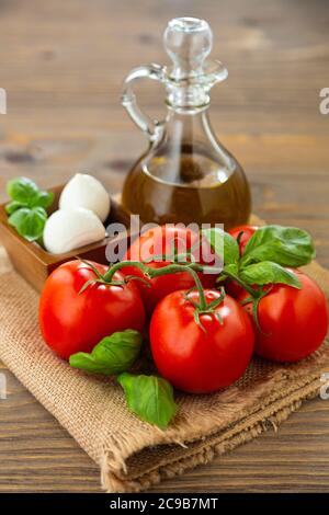 Ingrédients pour la salade Caprese sur une serviette en toile de jute sur fond de bois sombre. Banque D'Images