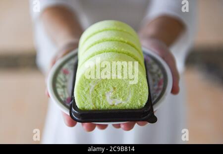 rouleau de gâteau sur l'assiette / une femme a servi le rouleau de gâteau vert pandan avec la crème Banque D'Images