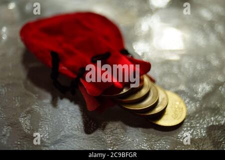 Pièces d'or dans une pochette rouge sur une table en verre Banque D'Images