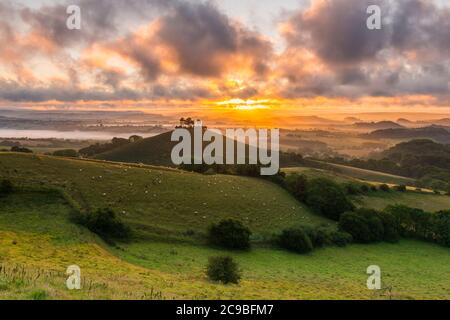 Bridport, Dorset, Royaume-Uni. 30 juillet 2020. Météo Royaume-Uni. Un lever de soleil spectaculaire à Colmers Hill près de Bridport dans Dorset tandis que le soleil levant envoie des rayons du soleil qui brillent à travers les nuages bas avant une journée d'été chaude prévue. Crédit photo : Graham Hunt/Alamy Live News Banque D'Images