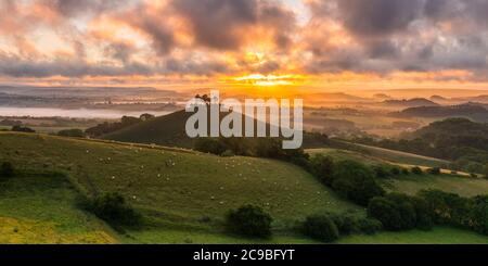 Bridport, Dorset, Royaume-Uni. 30 juillet 2020. Météo Royaume-Uni. Un lever de soleil spectaculaire à Colmers Hill près de Bridport dans Dorset tandis que le soleil levant envoie des rayons du soleil qui brillent à travers les nuages bas avant une journée d'été chaude prévue. Crédit photo : Graham Hunt/Alamy Live News Banque D'Images