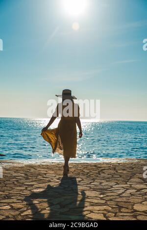 Jolie jeune femme en robe jaune à pied par stone beach Banque D'Images