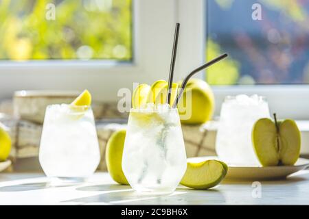 Cocktail d'été avec pomme verte et glace sur la table blanche près de la fenêtre en été ensoleillé. Image à mise au point sélective avec espace de copie Banque D'Images