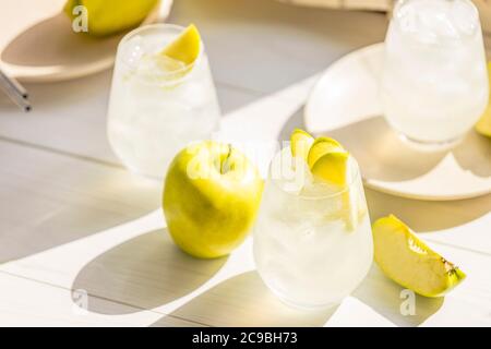 Cocktail d'été avec pomme verte et glace sur la table blanche près de la fenêtre en été ensoleillé. Image à mise au point sélective avec espace de copie Banque D'Images