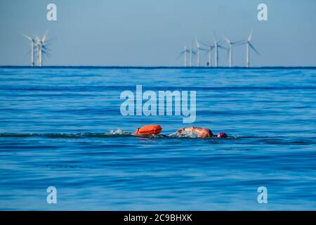 Worthing Beach, Worthing, Royaume-Uni. 30 juillet 2020. Les baigneurs en eau libre apprécient la mer calme du matin. Avec un ciel bleu clair et des eaux plates, les paddle-boards profitent du petit matin au large de la côte du sussex. Rampion Wind Farm peut être vu 13-20km au large. Photo par crédit : Julie Edwards/Alamy Live News Banque D'Images