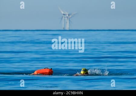 Worthing Beach, Worthing, Royaume-Uni. 30 juillet 2020. Les baigneurs en eau libre apprécient la mer calme du matin. Avec un ciel bleu clair et des eaux plates, les paddle-boards profitent du petit matin au large de la côte du sussex. Rampion Wind Farm peut être vu 13-20km au large. Photo par crédit : Julie Edwards/Alamy Live News Banque D'Images