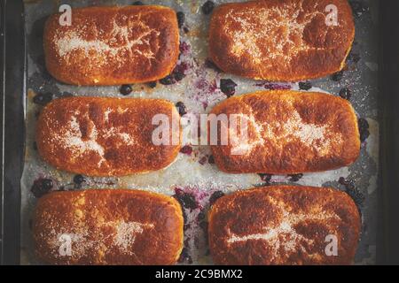 Délicieux petits pains chauds faits maison farcis aux myrtilles sur un plateau de cuisson Banque D'Images
