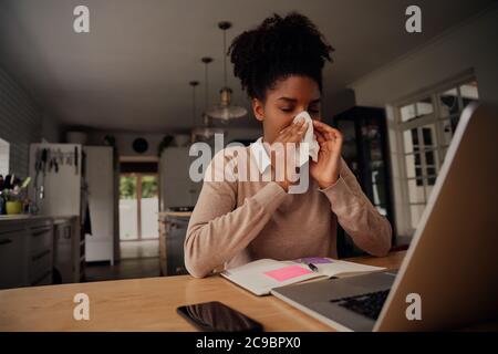 Malade épuisé jeune femme souffrant du virus du rhume et toussant en utilisant des serviettes en papier tout en travaillant à la maison Banque D'Images