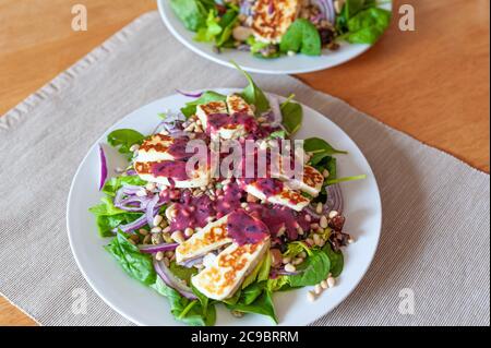 Salade de légumes frais et sains avec des morceaux de fromage de chèvre halloumi grillé et une délicieuse sauce aux myrtilles sur le dessus. Banque D'Images