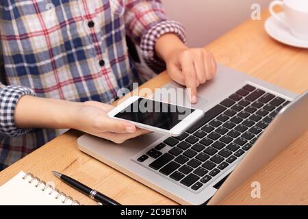 Les personnes travaillant à domicile à l'aide de smart phone et l'ordinateur portable sur le lieu de travail, visage anonyme concept marketing internet. Banque D'Images