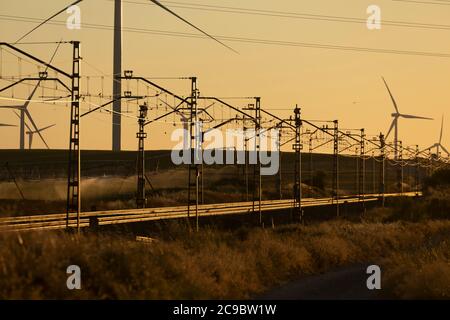 Voies ferrées superposées sur un paysage de silhouettes d'éoliennes en fonctionnement m dans la Ribera Alta del ebro, à Aragon, en Espagne. Banque D'Images