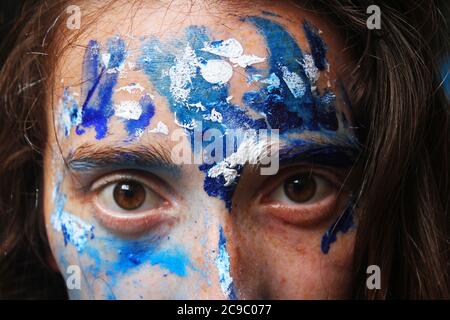 Face peinte en acrylique bleu et blanc. Jeune belle femme portrait, gros plan photo. Banque D'Images