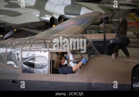 Samantha Archetti, conservateur préventif, nettoie le poste de pilotage d'un bombardier Avro Lancaster au Musée impérial de la guerre de Duxford alors que l'attraction se prépare à rouvrir au public samedi après l'assouplissement des restrictions de confinement en Angleterre. Banque D'Images