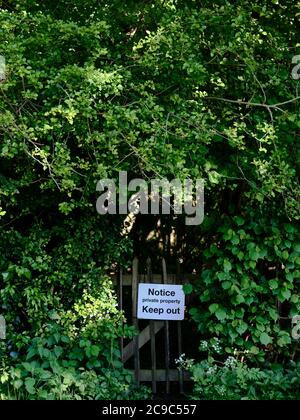 Un panneau d'avertissement de protection de la propriété privée sur une porte d'entrée dans un boisé d'été vert - nature garder à l'extérieur - terrain privé Banque D'Images