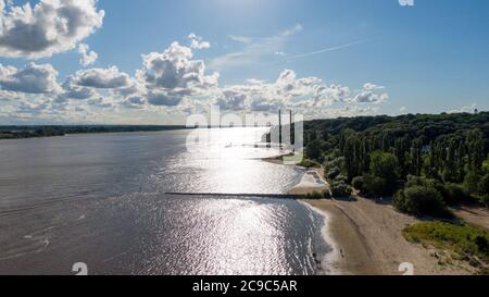 Hambourg, Allemagne. 11 juillet 2020. Les gens marchent le long de la plage d'Elbe dans des fissures tandis que le soleil se reflète sur l'eau (vue aérienne avec un drone). En arrière-plan, vous pouvez voir les tours de la centrale électrique de Wedel. Credit: Jonas Walzberg/dpa/Alay Live News Banque D'Images