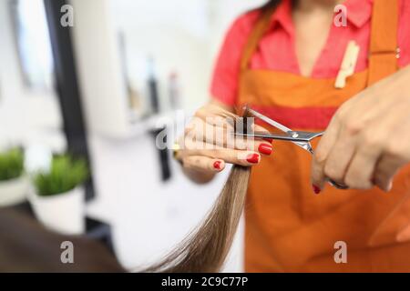 Femme coiffeur tient les cheveux et les moulins leurs extrémités Banque D'Images