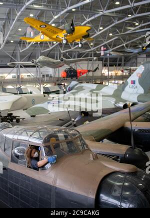 Samantha Archetti, conservateur préventif, nettoie le poste de pilotage d'un bombardier Avro Lancaster au Musée impérial de la guerre de Duxford alors que l'attraction se prépare à rouvrir au public samedi après l'assouplissement des restrictions de confinement en Angleterre. Banque D'Images