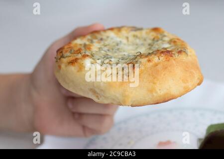 l'enfant à la main prend le soin de l'assiette. tarte maison avec fromage et herbes pour le petit déjeuner Banque D'Images