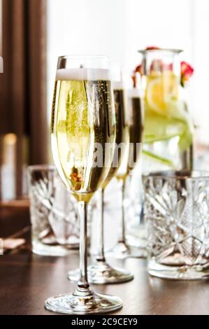 Table posée avec trois verres de champagne et carafe, et des verres de limonade en cristal sur fond de bokeh. Banque D'Images