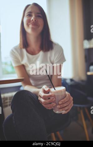 Femme boit le lait de matcha rose dans le café.ambiance de relaxation.image floue, foyer sélectif Banque D'Images