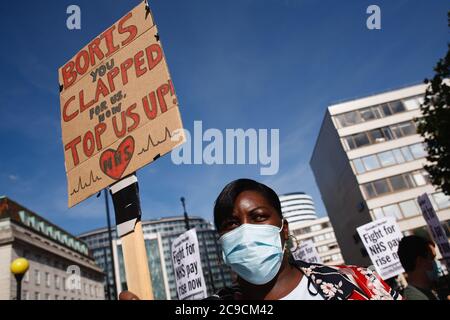 Un personnel du National Health Service (NHS) portant un masque est vu pour protester contre leur exclusion d'une augmentation de salaire récemment annoncée dans le secteur public, Faites une démonstration à l'extérieur de l'hôpital St Thomas de Londres.près de 900,000 travailleurs du secteur public au Royaume-Uni sont sur le point de recevoir une augmentation de salaire supérieure à l'inflation cette année comme un geste de gratitude de la part du Trésor pour leurs efforts pendant la pandémie du coronavirus. L'augmentation de salaire est toutefois réservée aux infirmières et autres membres du personnel de première ligne en raison d'un accord de rémunération de trois ans négocié en 2018, qui les a conduits à marcher sur la rue du Parlement en direction de Downing Street à Lo Banque D'Images