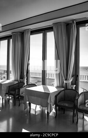 Les tables d'un hôtel avec une vue splendide sur la mer de la fenêtre. La lumière entre par la fenêtre le jour de l'été. Vacances, détente, luxe, Banque D'Images