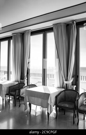 Les tables d'un hôtel avec une vue splendide sur la mer de la fenêtre. La lumière entre par la fenêtre le jour de l'été. Vacances, détente, luxe, Banque D'Images