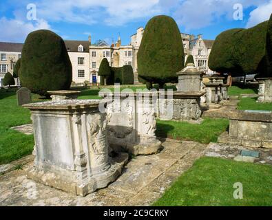 Église Sainte-Marie-la-Vierge, Painswick, Gloucestershire, monuments de cimetière, arbres à ragoûts tronqués, maisons et boutiques sur la rue principale Banque D'Images