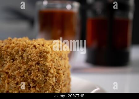 une tasse de thé dans un verre à double botoom, une théière à pression française et un morceau de gâteau sur une table blanche dans la cuisine grise. Photo de haute qualité Banque D'Images