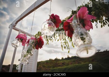 Décoration florale originale sous forme de mini vases et bouquets de fleurs accrochés à l'autel de mariage, cérémonie de mariage sur la plage extérieure Banque D'Images