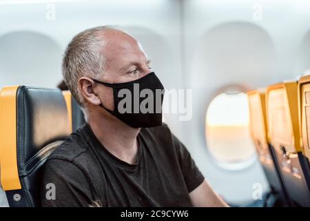 Homme portant un masque de protection assis dans l'avion Banque D'Images