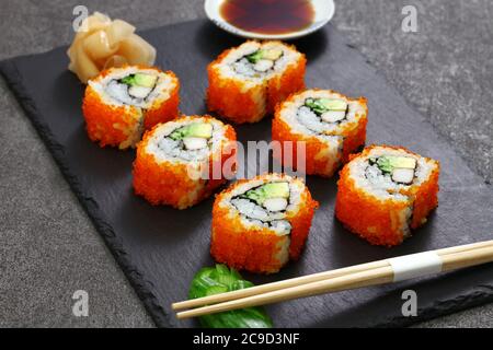 rouleaux de californie faits maison, fou de bâtonnets de crabe, avocat, concombre à l'intérieur. tobiko (œufs de poisson volant) à l'extérieur. Banque D'Images