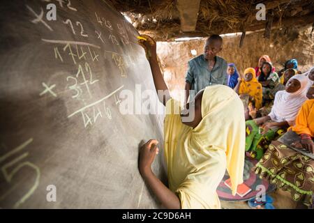 Oumou Garba (10) suit un cours d'alphabétisation fonctionnelle dans la région de Tahoua, au Niger. Dans le cadre du projet Alliance de 12/12, les femmes qui n'ont jamais reçu d'éducation, acquièrent des compétences de base en mathématiques et en lecture qui, entre autres choses, les aideront à mieux mener l'agriculture en tant qu'entreprise. Projet Alliance 12/12 - Niger, Afrique de l'Ouest. 18 septembre 2018. Photo de Jake Lyell pour le secours luthérien du monde. Banque D'Images