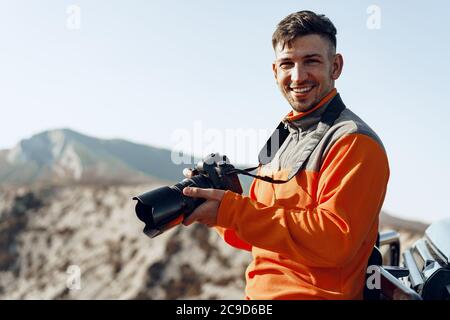 Jeune homme voyageur prenant des photos de montagnes avec un appareil photo professionnel Banque D'Images