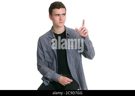 Un jeune homme dans une chemise de Manatee, un t-shirt noir et un pantalon, isolé sur blanc, pointe vers le haut à l'espace d'écriture Banque D'Images