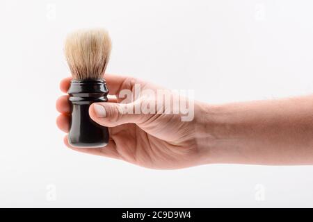 Main tenant une brosse de rasage sur fond blanc Banque D'Images