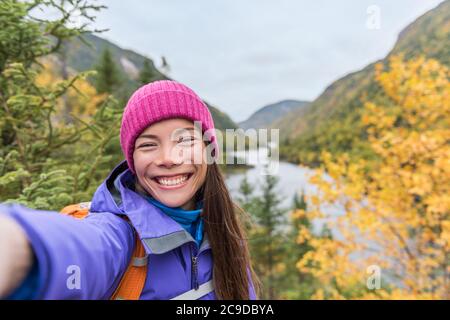 Selfie asiatique fille randonnée dans la nature automne montagnes. Une bonne randonneur prend une photo de smartphone en tenant son téléphone au point de vue pittoresque de la montagne d'automne Banque D'Images