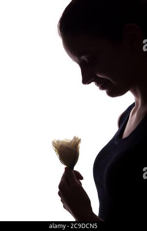 Jeune femme regarde devant avec fleur - vertical, silhouette isolée d'une vue latérale Banque D'Images