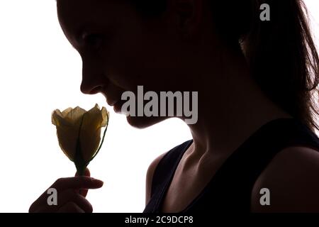 Une jeune femme sniffs une fleur - silhouette horizontale isolée d'une vue latérale Banque D'Images