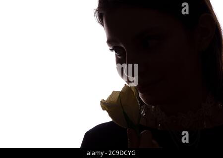 Une jeune femme sniffs une fleur - silhouette horizontale isolée d'une vue latérale Banque D'Images