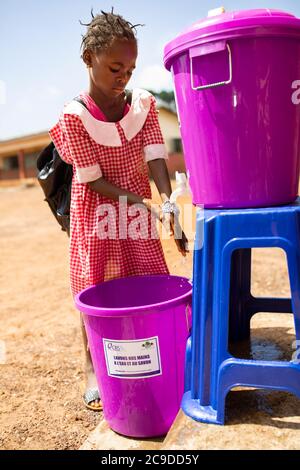 Une jeune fille se lave les mains à un poste de lavage des mains de son école à Conakry, Guinée, Afrique de l'Ouest. Banque D'Images