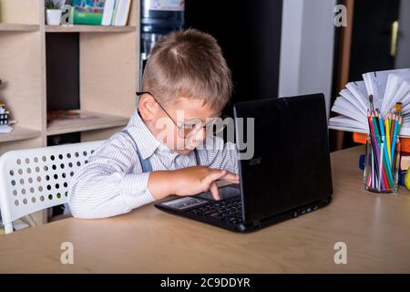 Un petit garçon fait ses devoirs. Le concept de l'apprentissage à distance. Banque D'Images