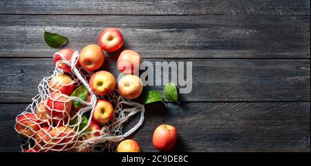 Sac à ficelle et pomme rouge sur fond en bois. Pommes mûres sur table et espace de copie vintage. Saison d'été ou d'automne. Banque D'Images