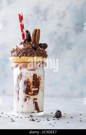 Délicieux milkshake glaçant au chocolat avec beignets et bonbons. Tendance à la fréakshake. Copier l'espace Banque D'Images